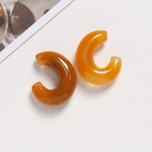 Detail of C-shaped resin earrings with translucent brown marble ink texture