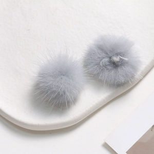 Detailed view of soft grey 3.5cm mink fur pom-poms for DIY jewelry on white tray