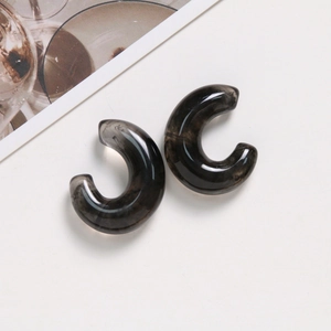 Macro detail of translucent smoky gray resin C-shaped earrings with ink marble texture