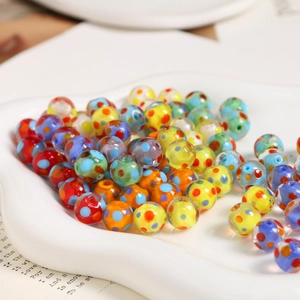 Macro shot of 10mm colorful polka dot glass beads on a white porcelain dish for DIY jewelry