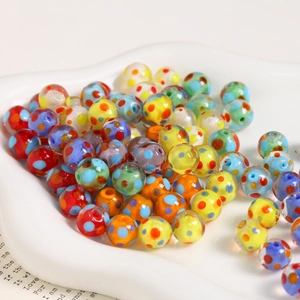 Macro shot of 10mm multi-colored lampwork glass beads with polka dots in a ceramic dish