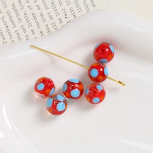 Detail of red handmade glass beads with blue and orange dots for jewelry making