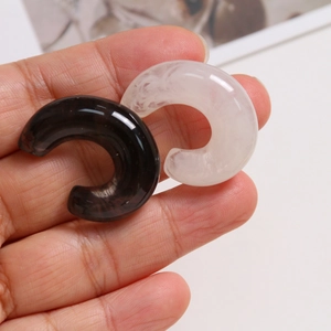 Detailed close-up of C-shaped resin charms with ink-wash texture and marble patterns