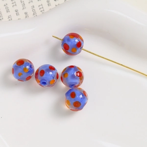 Macro view of 10mm light blue glass beads with colorful dots and pre-drilled holes