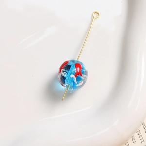 Détail macro d'une perle en verre bleu de 12mm avec poisson rouge pour bijoux DIY