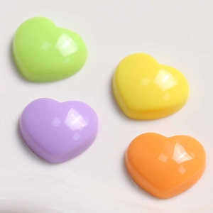 Close-up of four glossy heart-shaped acrylic charms in pastel green, yellow, purple, and orange