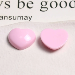 Macro shot of glossy pink heart-shaped resin charms for DIY jewelry and hair accessories