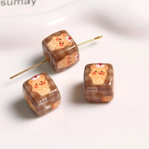 Macro detail of cube-shaped DIY beads with brown check pattern and cake bear print