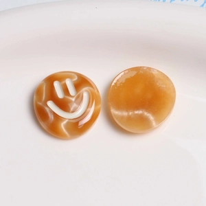 Detail of amber marble resin smiley face charms for DIY hair clips and jewelry making