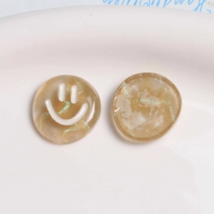 Macro detail of amber resin smiley face charms with glitter and flowing sand texture