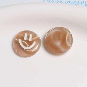 Macro shot of two brown resin smiley face charms for DIY hair accessories and jewelry