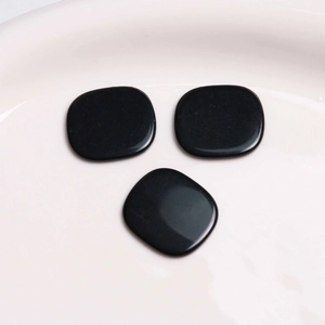 Close-up of polished black resin square cabochons for DIY jewelry and hair accessories