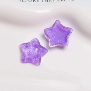 Macro view of purple glitter star resin charms for DIY jewelry and hair accessories