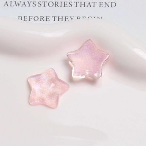 Close-up of pink glittery star-shaped resin charms on white ceramic plate for DIY crafts