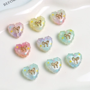 Macro detail of heart resin charms with gold bows and star sequins for DIY crafts