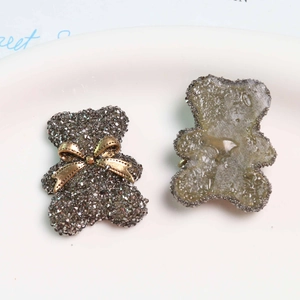 Detail of grey bear resin charms with micro-rhinestones and gold bows for DIY crafts