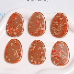 Oval resin pendants with dried flower wood chips for DIY jewelry making on white tray