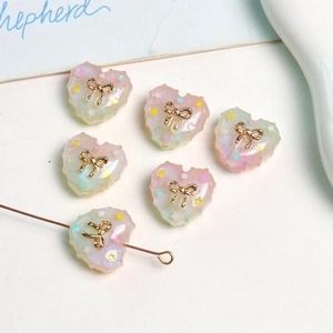 Macro view of gradient resin heart charms with gold bow and glitter star inclusions