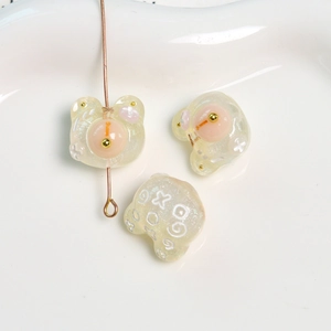 Primer plano de dijes de oso de resina brillante con diseños X y O para joyería DIY