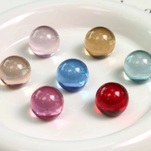 Perles en résine colorées transparentes dans un bol blanc pour la création de bijoux DIY
