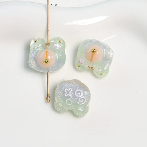 Detalle de dije de oso de resina con purpurina y toques dorados para joyería y accesorios