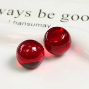 Vue détaillée de deux perles en résine rouge translucide sur un plateau pour bijoux DIY