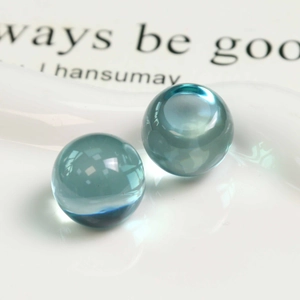 Vue macro de deux perles en résine bleu clair translucide sur un plateau blanc pour DIY