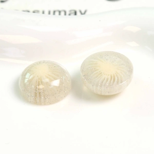 Detailed close-up of milky white resin charms with radial patterns and silver glitter flakes