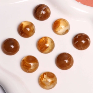 Neuf cabochons de 18mm en résine ambre avec texture marbrée blanche sur plateau blanc