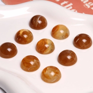 Macro de cabochons en résine marbrée ambre 18mm sur assiette en céramique blanche