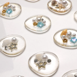 Macro detail of resin charms with sea shells, pearls, and gold stars for DIY crafts
