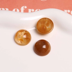 Vue macro de cabochons ronds en résine ambre de 18 mm avec texture marbrée dans un plat en céramique