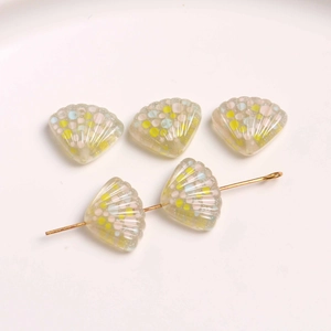 Detail van glitterhars schelphangers met kleurrijke stippen op gouden pin voor DIY-sieraden