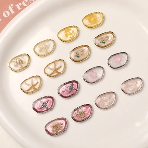 Detailed view of oval DIY metal charms featuring starfish, shells, and dried flowers