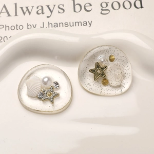 Macro detail of resin shell and star charms with gold glitter for DIY crafts