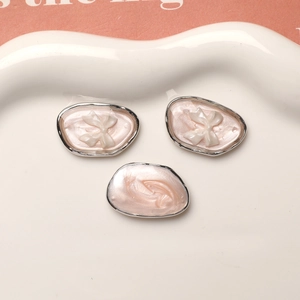 Close-up of pink pearlescent resin pendants with white bows in a ceramic dish