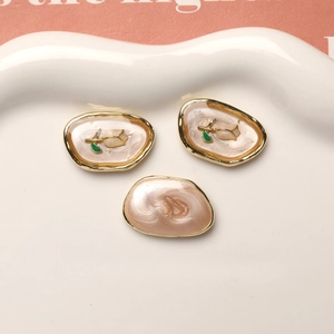 Detailed close-up of oval alloy flower and starfish DIY earring charms on ceramic tray