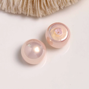 Macro detail of two light pink pearlescent half-hole beads for DIY jewelry making