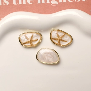 Macro detail of starfish pendants and pearlescent resin charms on a ceramic tray