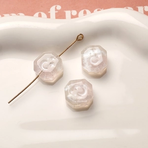 Primer plano de cuentas de resina con brillo y grabados de luna y estrella para joyería DIY