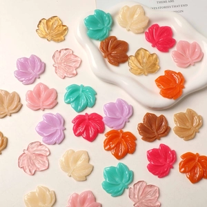 Colorful resin maple leaf charms for DIY earrings and crafts on white ceramic plate