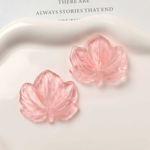 Macro detail of translucent pink resin maple leaf charms with frosted texture for DIY jewelry