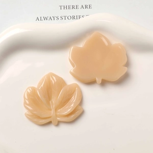 Macro detail of resin maple leaf charms showing front texture and flat back for DIY