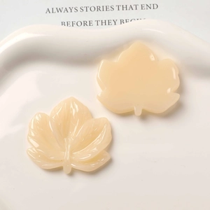 Macro view of cream maple leaf resin charms with detailed vein textures for DIY crafts
