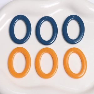 DIY jewelry parts featuring oval resin pendants in navy blue and amber orange colors