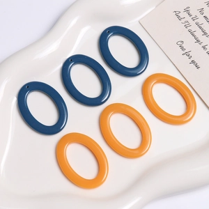 Flat lay of teal blue and orange oval resin charms on a white wavy ceramic tray