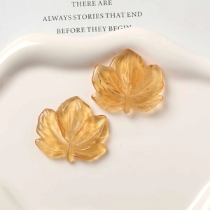 Macro shot of amber resin maple leaf charms with detailed veins for DIY jewelry making