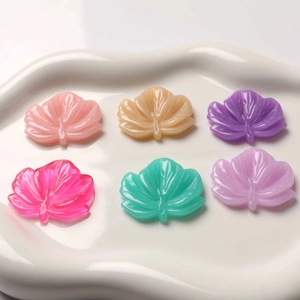 Vibrant resin maple leaf DIY charms in multiple colors arranged on a white ceramic plate