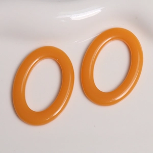 Close-up of vibrant orange oval resin charms for DIY earrings and handmade jewelry