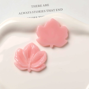Macro shot of pink resin maple leaf charms showing front texture and flat back